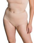 Woman wearing an ada light nude organic cotton high rise brief bottom on a white background