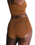 Woman wearing an ella deep nude high rise organic cotton brief bottom on a white background, back