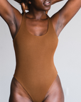 model showing front view of ella nude, brown, bodysuit. Scoop style, thong bottom.