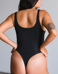 Back view of model wearing black bodysuit, thong style.