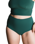 Person wearing a lagoon dark green organic cotton high-waisted brief bottom on a white background
