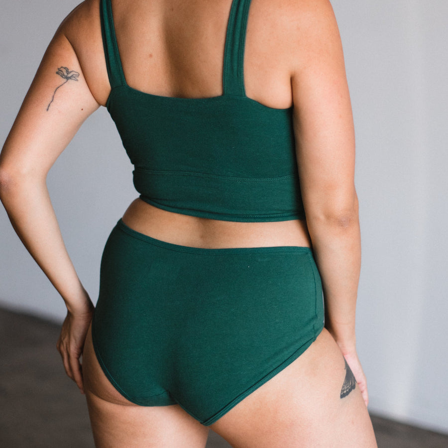 back view of model wearing mid rise brief in lagoon dark green teal.