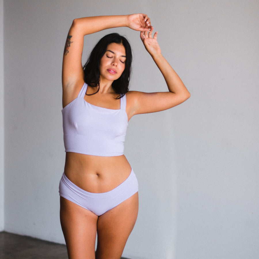 model with hands over head wearing lilac square neck bralette and mid rise briefs